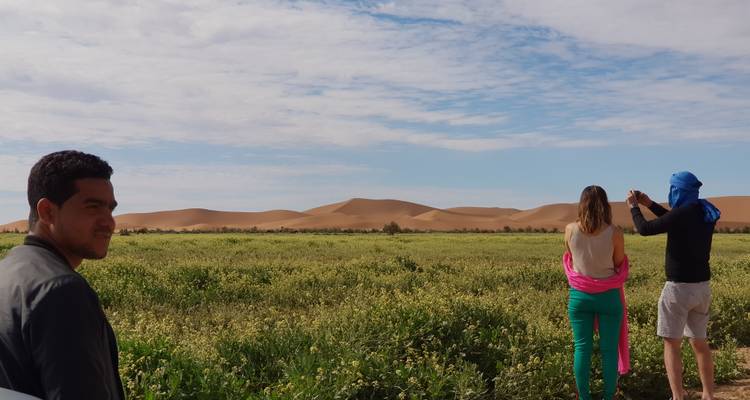 Des gens debout dans un champ avec des dunes de sable en arrière-plan.