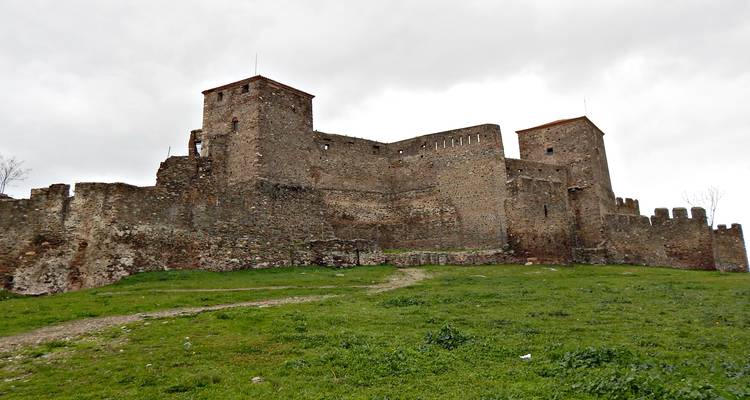 Murallas de fortaleza antigua con un primer plano cubierto de hierba.