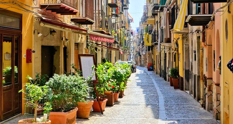 Pintoresca calle estrecha con plantas en macetas y edificios vibrantes.