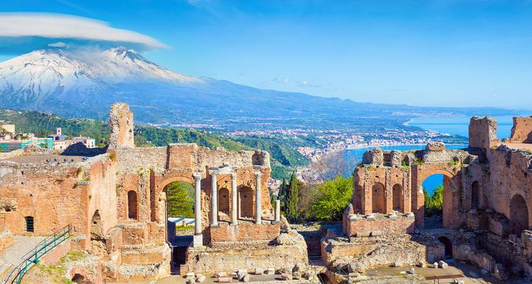 Ruinas antiguas con el Monte Etna al fondo con vista al mar.