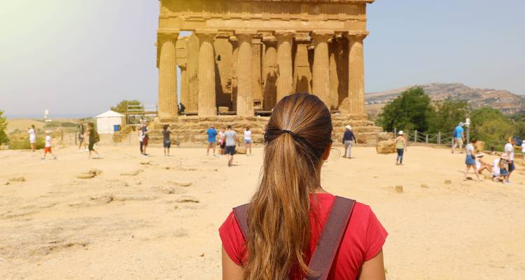 Touriste regardant un temple ancien avec des gens qui se promènent autour.