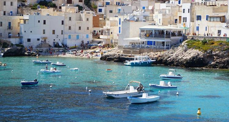 Weißes Küstendorf und kleine Boote auf dem strahlend blauen Wasser der Insel Favignana.