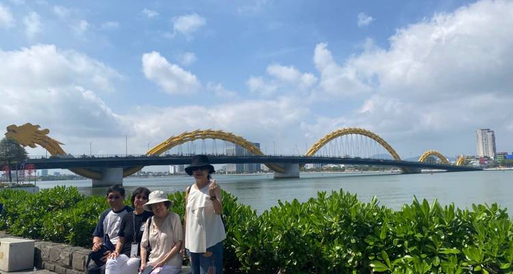 Petit groupe posant à côté de l'emblématique pont du Dragon jaune de Da Nang qui s'étend sur la rivière