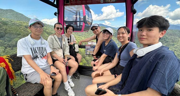 Amis voyageant dans un téléphérique en verre au-dessus de montagnes verdoyantes par une journée ensoleillée