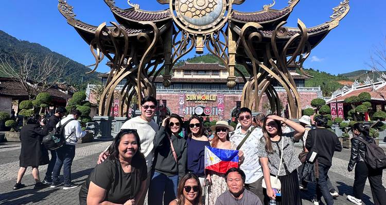 Groupe de touristes joyeux avec drapeau se rassemble à la sculpture d'entrée ornée de Sun World Ba Na Hills.
