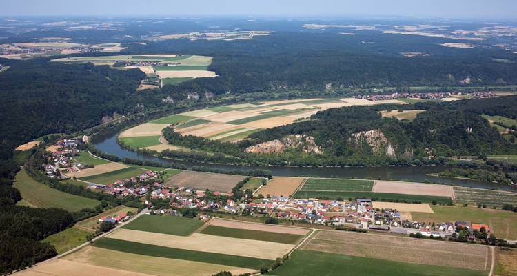 Aerial view of a river winding through a landscape with fields and woods.