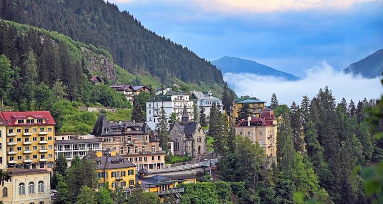 Vue d'une ville nichée dans une vallée de montagne avec une couverture nuageuse.