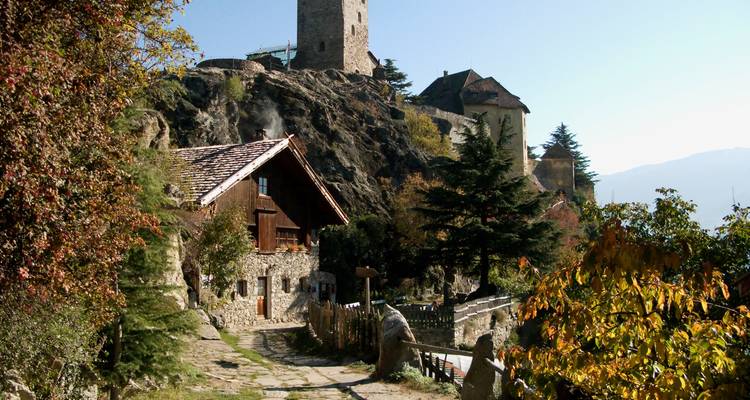 Stone buildings on a hillside with lush green trees.