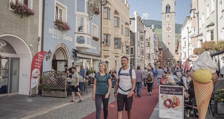 Rue bondée avec des bâtiments historiques et des gens qui marchent.