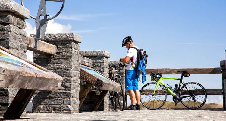 Man with a bicycle on a mountain overlook.