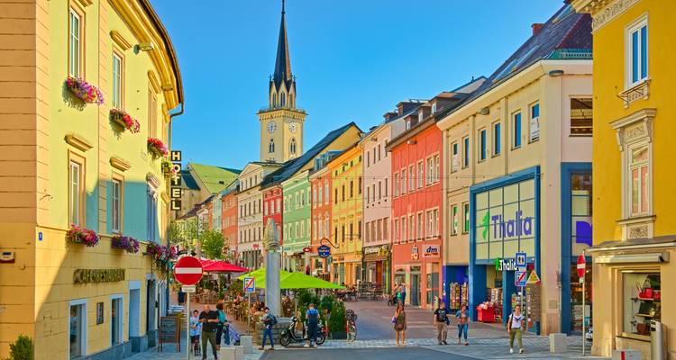 Colorful street scene with people walking and shopping.