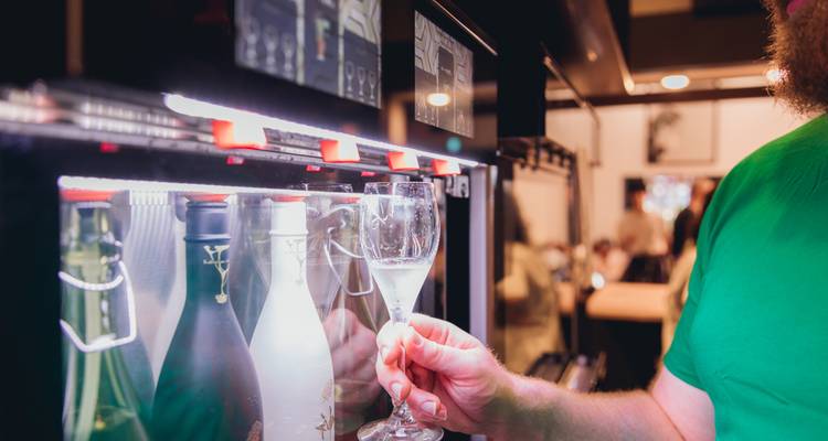 A hand holding a glass of sake in a tasting room.
