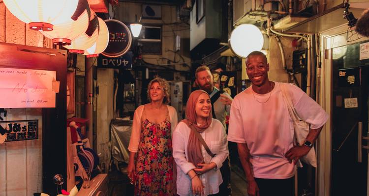 A group of friends exploring a narrow alley filled with lanterns at night.