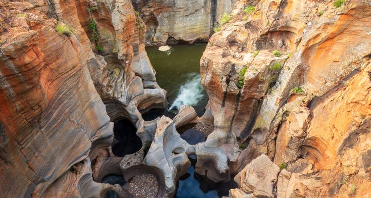 Geërodeerde, ingewikkelde rotsformaties met een kleine waterval.