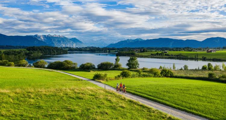 Radfahrer auf einem Weg mit malerischem Blick auf Berge und Seen.