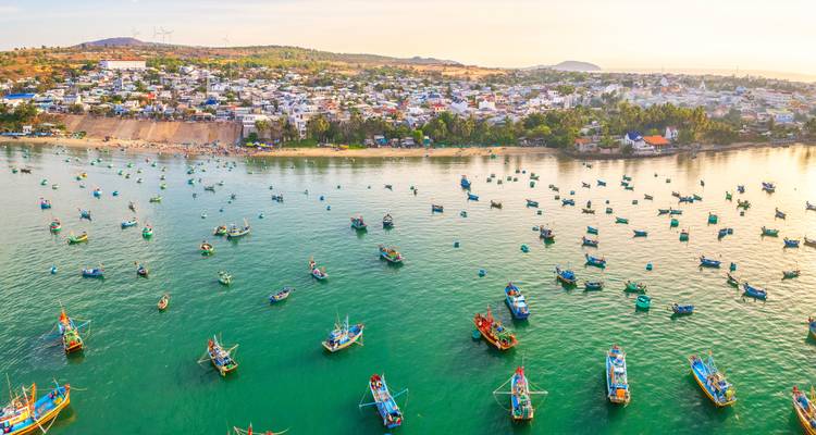 Aerial view of a coastal town with colorful fishing boats in the water.