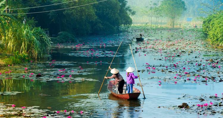 Mensen die een boot roeien op een rivier met bloemen.