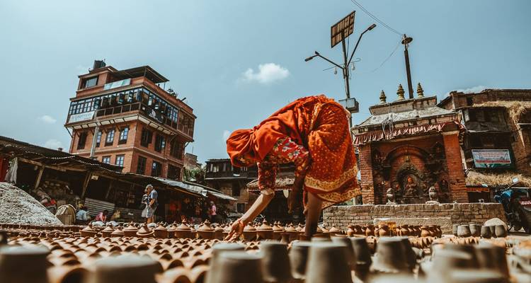 Persoon die aardewerk rangschikt in een buitenomgeving.