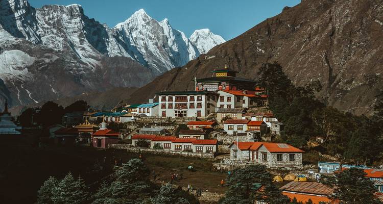 Dorp in een dal met met sneeuw bedekte bergen op de achtergrond.