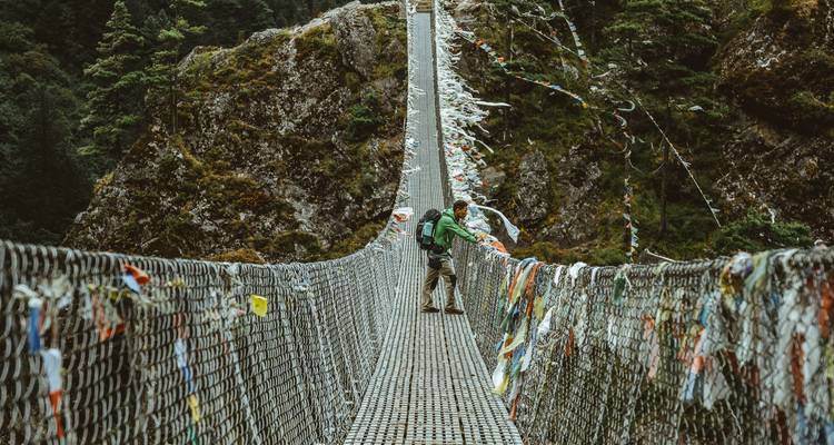 Hangbrug over een diepe kloof met gebedsvlaggen.