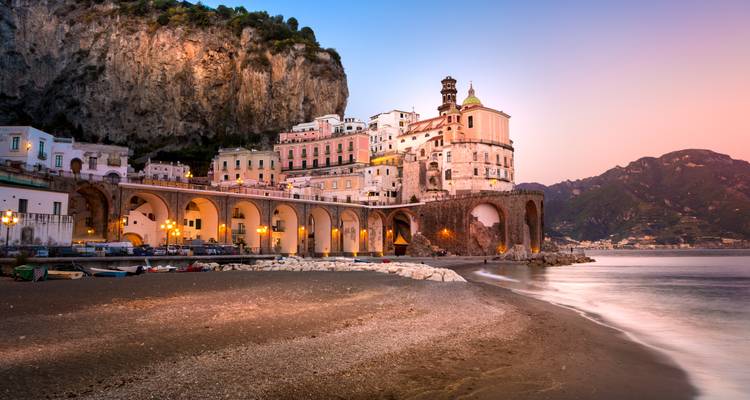 Malerische Küstenstadt mit beleuchteten Gebäuden in der Dämmerung.