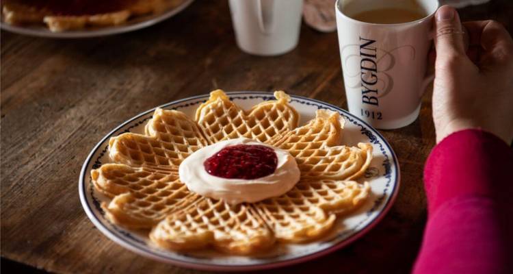 Assiette de gaufres avec garniture aux framboises servie avec du café.