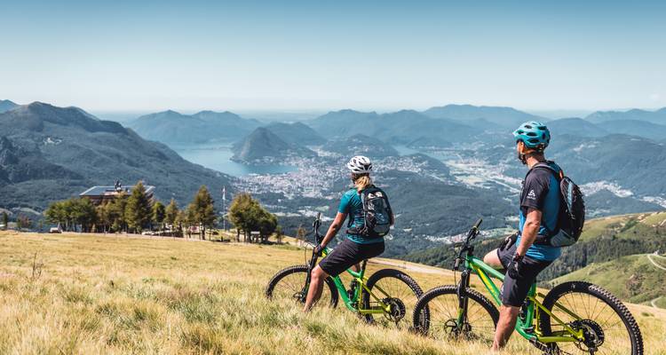 Bikers enjoying a panoramic mountain and lake view.
