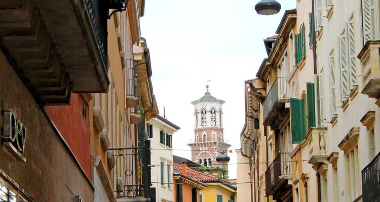 Narrow street with historical buildings leading to a tower.