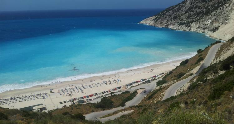 Strand met parasols en turquoise water.