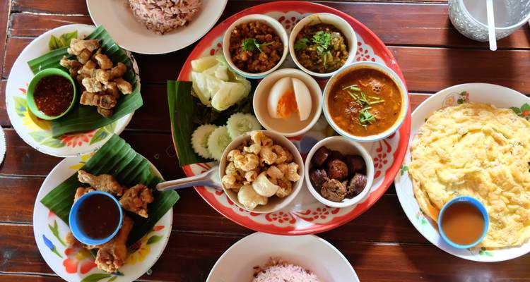 Traditionelle thailändische Gerichte serviert in kleinen Schalen auf einem Holztisch.