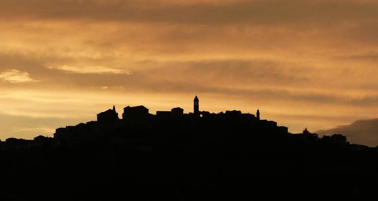 Silhouette d'une ville contre un ciel orange profond.