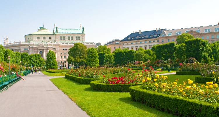 Historische Gebäude umgeben von einem lebendigen Garten unter klarem Himmel.