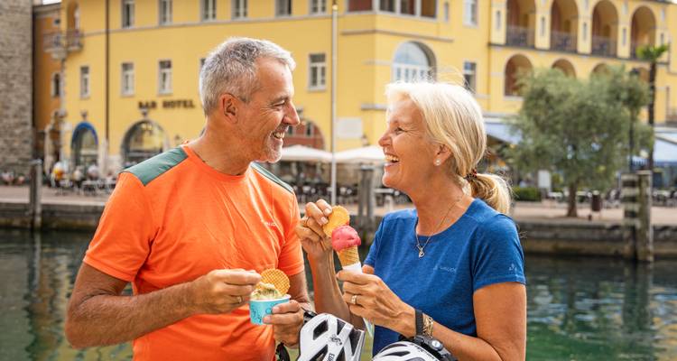 Two people sharing ice cream in a lakeside town.