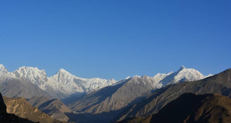 Panoramisch uitzicht op glanzende met sneeuw bedekte Himalaya-toppen onder een diepblauwe hemel