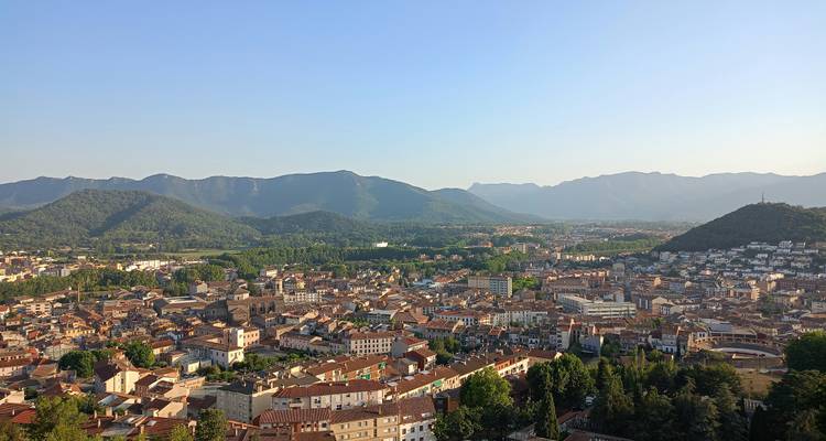 Panoramic view of a city nestled between green hills.