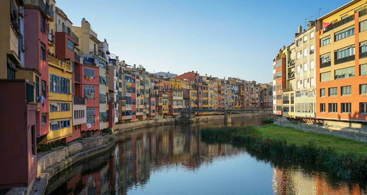 Colorful buildings lining a serene river in a charming city.