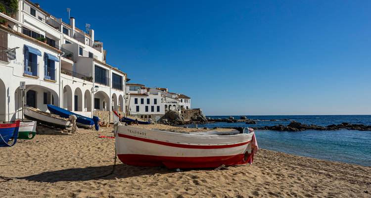 Sandy beach with boats and coastal houses.