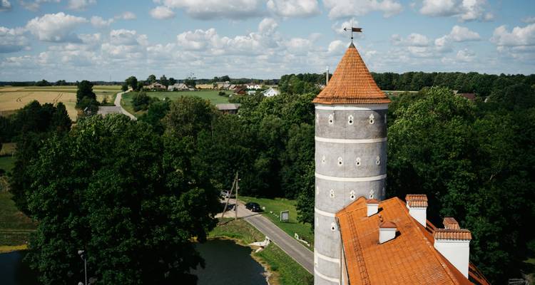 Ländliche Landschaft mit einem hohen zylindrischen Turm und Feldern.