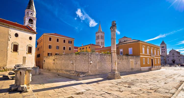 Historic buildings with stone columns and tiled rooftops under a clear blue sky.