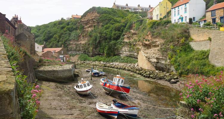 Coastal area with boats on a dry riverbed and colorful houses.