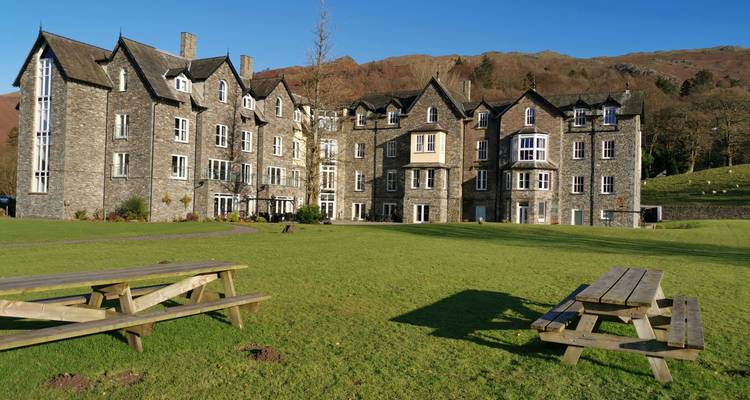 Large stone building with benches on grassy lawn.