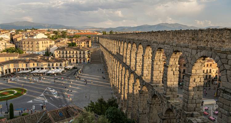 Aqueduc romain antique à Ségovie avec vue sur la ville et les montagnes.