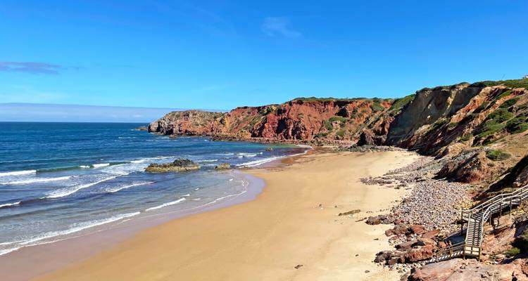A beautiful sandy beach with rocky cliffs and blue ocean.