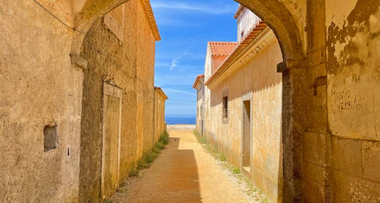 View through an archway of a narrow street leading to the ocean.