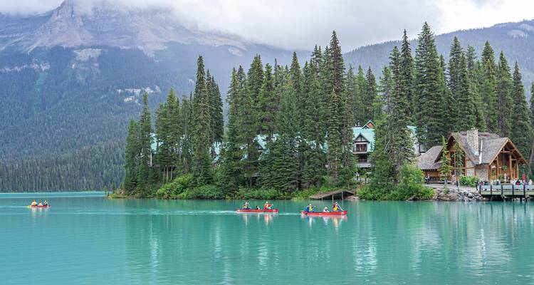 Des gens faisant du canoë sur un lac turquoise entouré d'arbres.