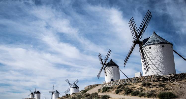 Rangée de moulins à vent traditionnels avec ciel bleu et nuages épars.