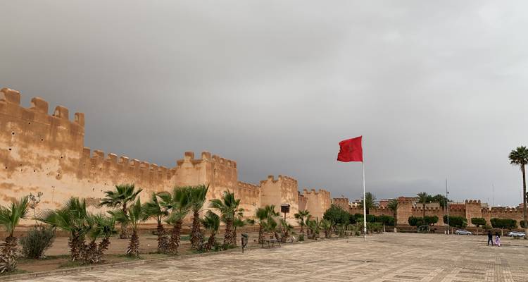 Historic city wall with a large red flag.