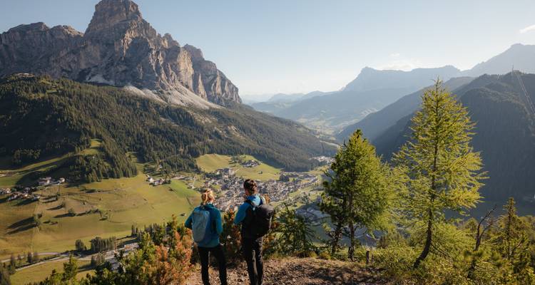 Two people enjoying a panoramic view of mountains and valleys under a clear sky.