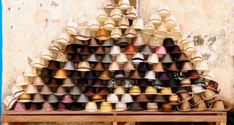 Pyramid of stacked hats against a rustic wall.