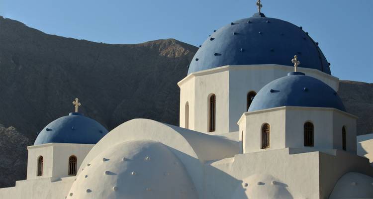 Nahaufnahme einer weißen Kirche mit blauen Kuppeln und Kreuzen.